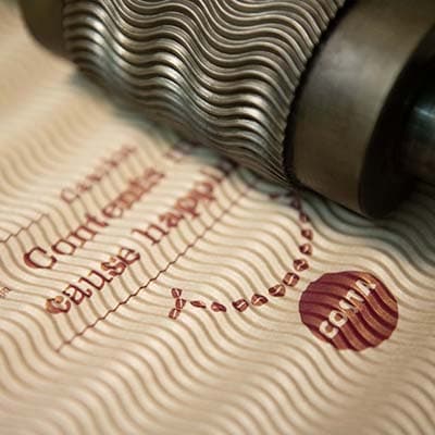 Embossing roller printing a wave and Costa Coffee branding pattern